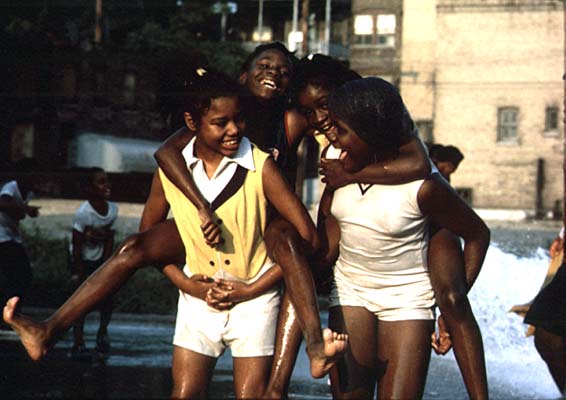 Black youngsters cool off with fire hydrant water on Chicago's South Side in the Woodlawn community. June 1973 (NWDNS-412-DA-13684)