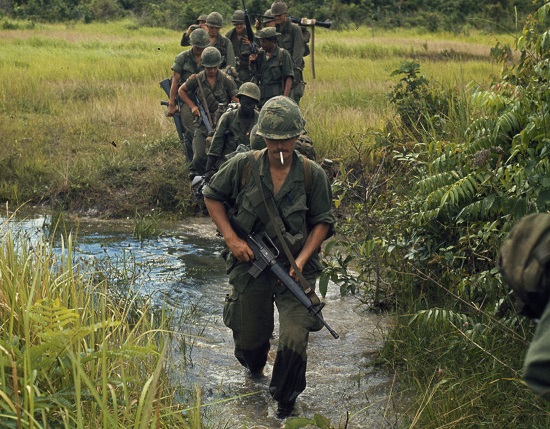 Soldiers marching through a rice paddy