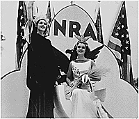 "NRA: posed shot of two woman dressed in costumes promoting National Recovery Administration programs with blue eagle emblem, NRA letters, and American flags in background," ca. 1934. (FDR Presidential Library NLR-PHOCO-A-74201379)