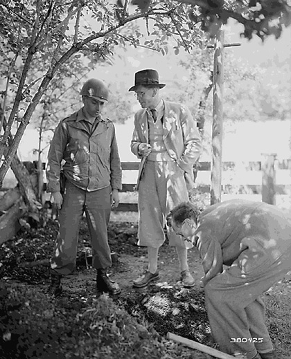SS Major Kurt Baron Haller Von Hallerstein admitted that he had buried nearly a million dollars worth of securities and jewelry near Garmisch, Germany.  Hallerstein (center) watches with Tec 4 Frederick Wolinsky, New York, NY, as his brother Helmuth Baron Haller Von Hallerstein, digs. May 25, 1945 