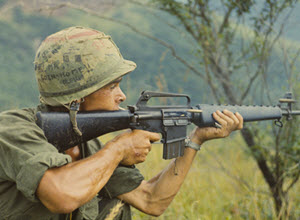 Photograph of Private Michael J. Mendoza Firing His M-16 Rifle Into a Valley during Operation Cook