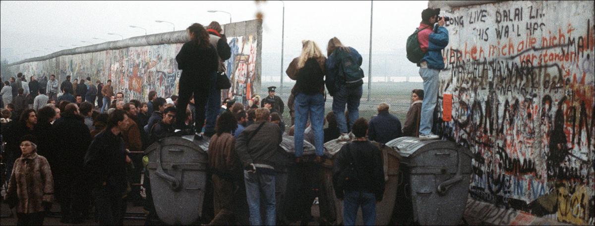 People look through the broken Berlin Wall