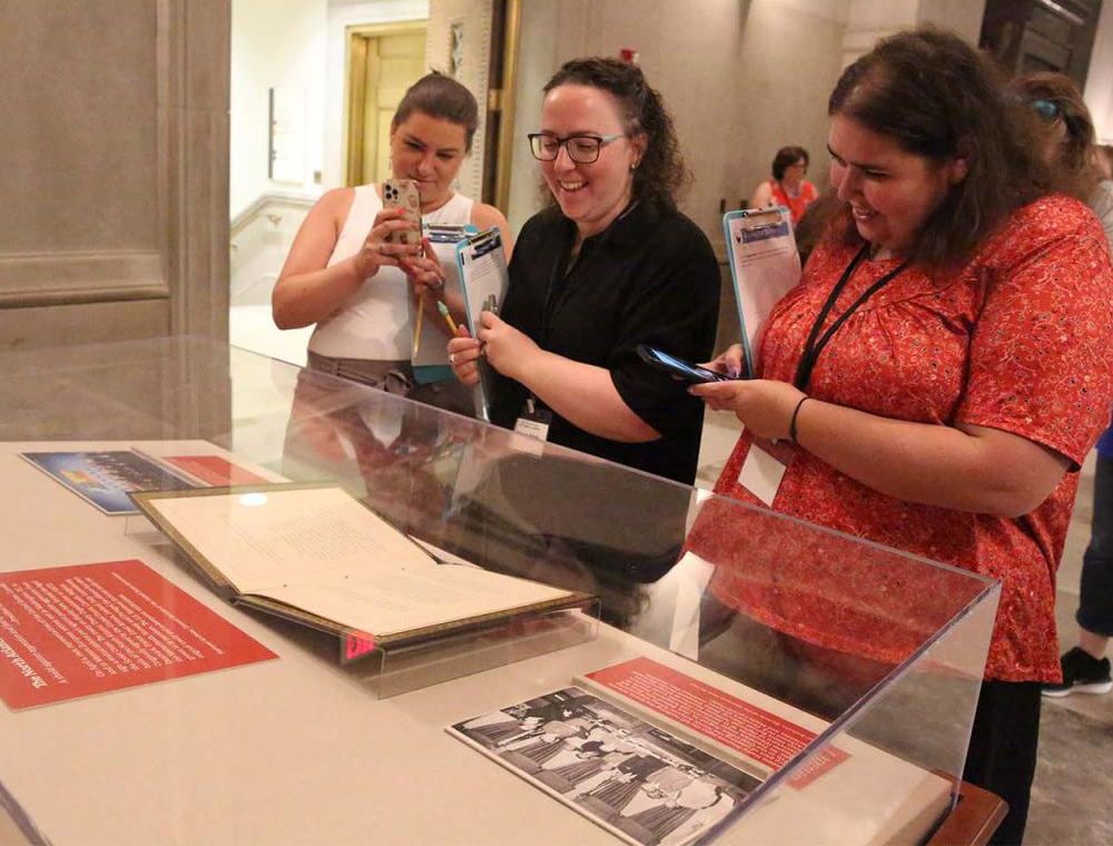 Three visitors look at the NATO Treaty on display in the National Archives Rotunda