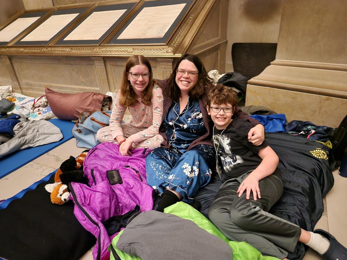 Color photograph of woman and two children in sleeping bags in the Rotunda 