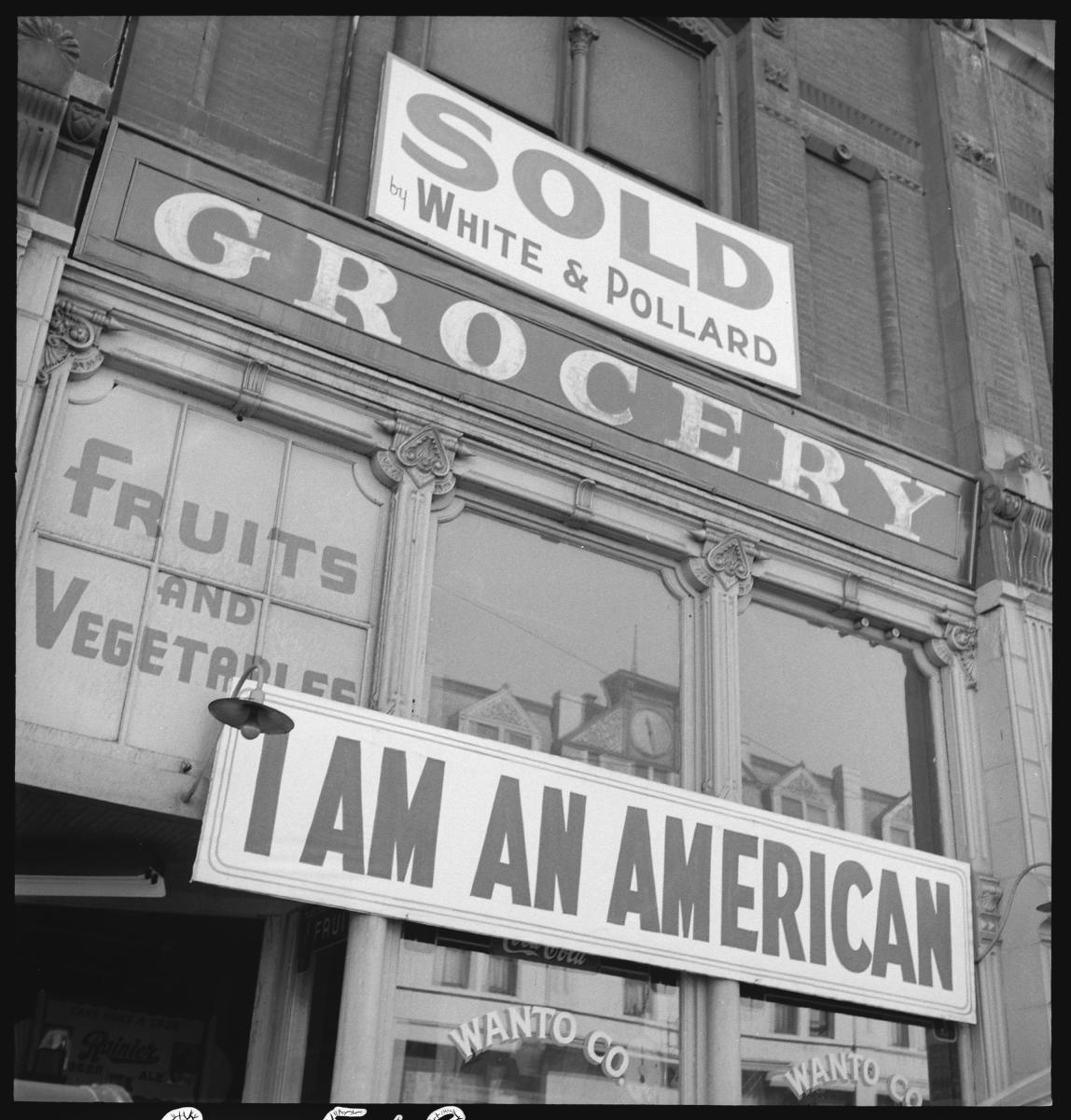 I am an American” sign hung by the storefront owner of Japanese descent the day after Pearl Harbor, photograph by Dorothea Lange.