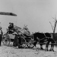 13. A refugee family leaving a war area with belongings loaded on a cart.
